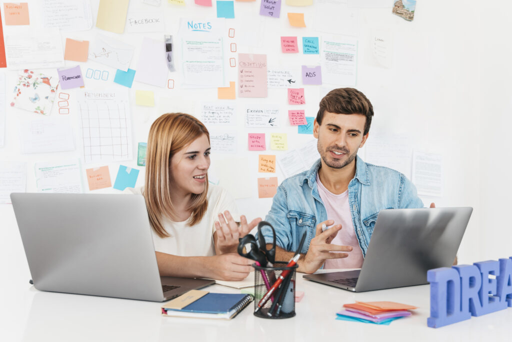 colleagues-discussing-video-seo-optimization-on-laptop-at-desk